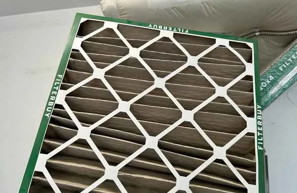 Pleated furnace air filter clogged with gray dust